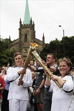 England, Kent, Tunbridge Wells, Olympic Torch relay runners handing over torch by exchanging the