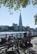 England, London, People relaxing on the North Bank of the river Thames with the Shard visible