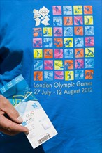 England, London, An Olympic spectator wearing an official T-shirt holding their official ticket for