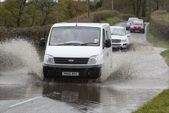 England, Kent, Flooding, Flooded country road with cars driving slowly through waters. Photo : Sean