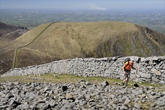 Ireland, County Down, Mourne Mountains, Hiker on Slieve Donard with Slieve Commedagh behind. Photo
