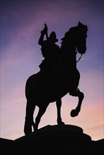 Spain, Madrid, Statue of King Philip II in Plaza Mayor silhouetted against evening sky. 
Photo
