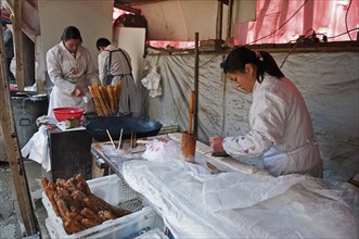 China, Jiangsu, Nanjing, Road-side bakery shop baker cutting strips of dough that will be twisted