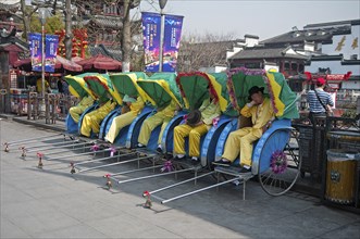 China, Jiangsu, Nanjing, Row of rickshaws with the rickshaw pullers in yellow uniform and hats