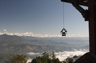 Nepal, Nagarkot, View across clouded valley towards Himalayan mountains wind chime hanging from