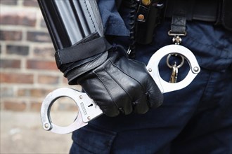 Law & Order, Crime, Police, Detail of Police officer wearing body armour and holding Hand Cuffs.