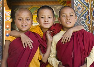Bhutan, Punakha, Three young novice monks standing in doorway of Chimi Lakhang temple in the old