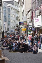 Turkey, Istanbul, Fatih, Sultanahmet, Men sat in street in readiness for midday prayers. 
Photo