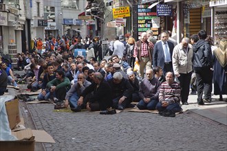 Turkey, Istanbul, Fatih, Sultanahmet, Men sat in street in readiness for midday prayers. 
Photo