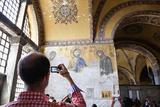 Turkey, Istanbul, Fatih  Sultanahmet  Tourist photographing religious mosiac in Haghia Sofia.