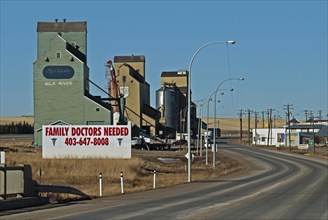 Canada, Alberta, Milk River, Old wooden grain silos or elevators still in use  Large sign announcing Family Doctors Needed for this small town near the USA border.