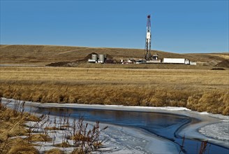 Canada, Alberta, Del Bonita, Fracking near a water source for tight shale oil and gas on the edge of the Bakken play. Ensign Energy of Calgary drilling rig  water storage tanks and road tanker. The wa...