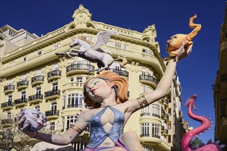Spain, Valencia Province, Valencia, Female Papier Mache figure with a horse on her head in the street during Las Fallas festival.