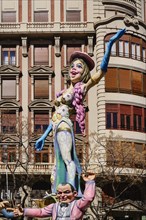 Spain, Valencia Province, Valencia, Papier Mache figure of a woman standing on another figures shoulders in the street during Las Fallas festival.