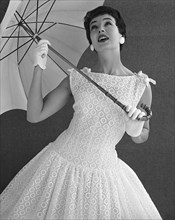Mannequin portant une robe nouée aux épaules et tenant une ombrelle