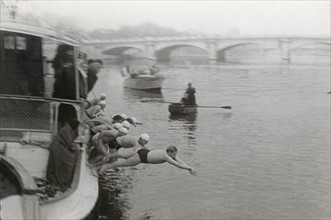 A series of swimmers is diving from a boat