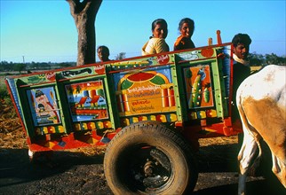 Famille rentrant à la maison dans une charette multicolore, sud du Karnataka, Inde.