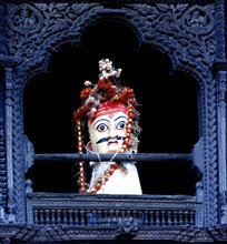 Curious idol in intricately carved window, Bhaktapur, Nepal, India.