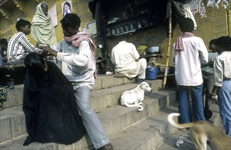 Homme se faisant couper les cheveux, près d'un ghât, Varanasi, Inde.