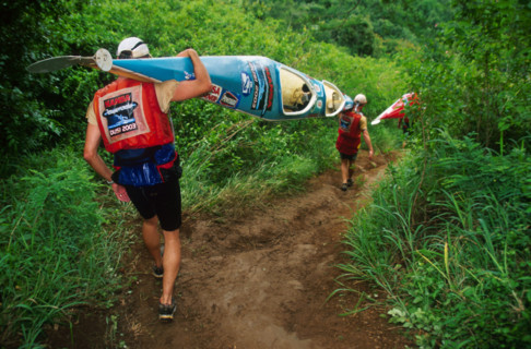 double canoe descending steep path through lush vegetation