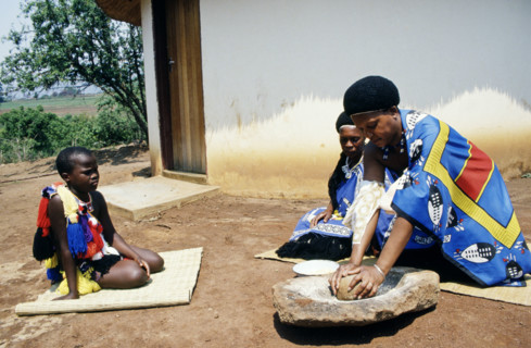 SWAZI WOMAN AND CHILDREN GRINDING MAIZE, SWAZILAND