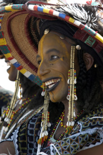 A Wodaabe man performs a dance of male beauty, showing off the whiteness of his teeth and eyes at a