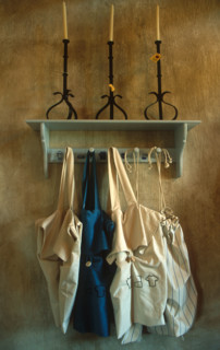 portrait view of aprons hanging from a shelf with candlesticks