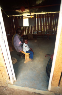 A Samburu child waits with his father or grandfather for medical attention at a mobile clinic set up in a school in the town of Wamba. Samburu men later on in life take young brides in their teens