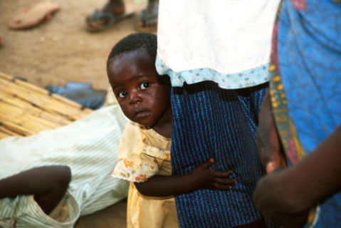 Child peers around mother