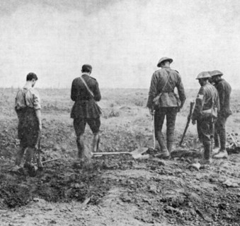 Premiere guerre mondiale : Aumonier militaire menant un service funeraire dans un champ aux cotes de soldats silencieux