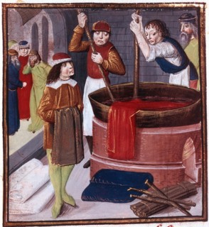 Des teinturiers plongent un pan de tissu dans une bassine de teinture placée sur le feu