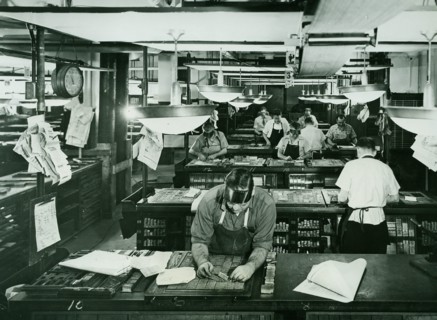 Compositors set metal type faces in a newspaper composition room