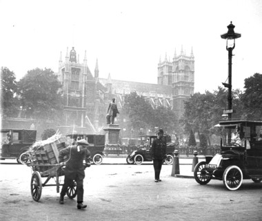 Street scene, Westminster, London, with cars, boy with handcart, and policeman on duty, c 1910.