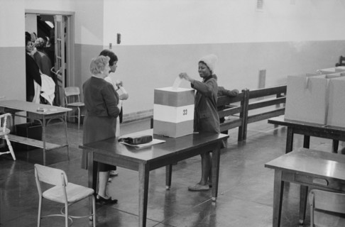 Young African American woman casting her vote in a ballot box