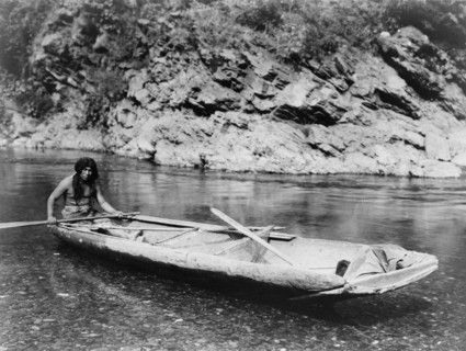 Native American Yurok Indian fisherman paddling a canoe on Trinity River
