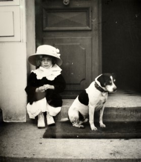 French girl photographed in a doorway with her pet dog, circa 1896