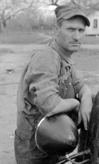 White migrant worker leaning on headlamp of his car near Harlingen, Texas. Migrants are called rubber tramps throughout Texas By Russell Lee, 1903-1986, photographer 19390101.
