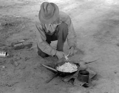 Migrant worker cooking meal over campfire, 19390101 .
