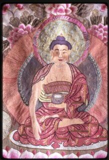 Photograph of a religious silk textile (thangka) depicting Buddha