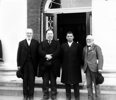 Robert C. Ogden, Senator William Howard Taft, Booker T. Washington and Andrew Carnegie, standing on the steps of a building, at the Tuskegee Institute
