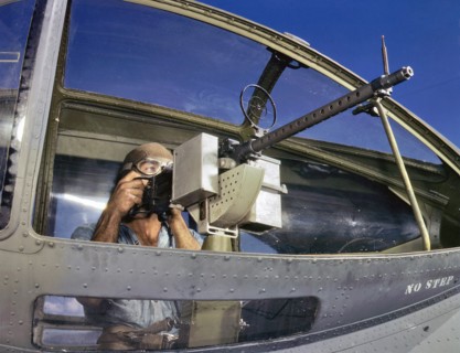 World War Two US Navy ordnance man, with a M1919 Browning machine gun next to a PBY Catalina aircraft 1942