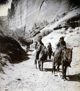Photograph of a band of mounted Navahos passing through the canon