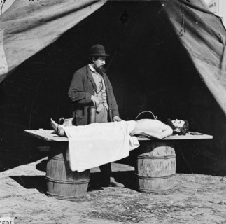 Unknown location. Embalming surgeon at work on soldier's body.