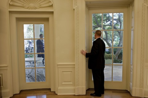US secret service agent in the oval office, prepares to open a door as President Obama approaches