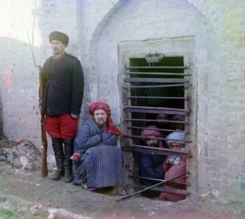 Zindan (prison), with inma: with inmates looking through the bars and a guard with Russian rifle, uniform and boots.