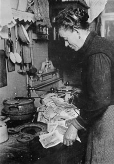 German woman starting a fire with a pile of marks