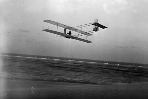 Three-quarter left rear view of glider in flight at Kitty Hawk