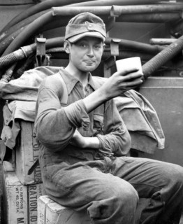 Photograph of a captured German boy soldier enjoying a cup of coffee aboard a U.S. Coast Guard Normandy coast.