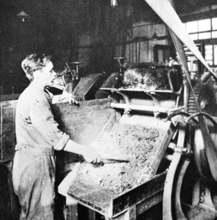 workman sorts ground graphite on a grinding machine