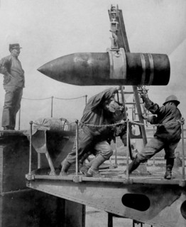 An artillery shell is hoisted into position by soldiers.